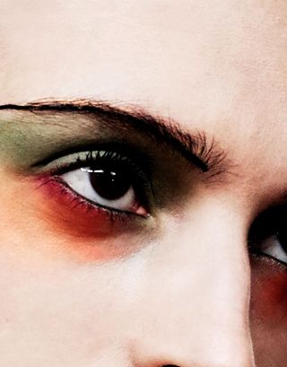close up shot of girl with green and orange eyeshadow and black line of eyebrow