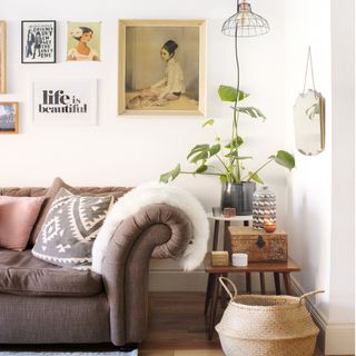 Cosy and comfy bohemian living room. Wall mounted pictures, life is beautiful print. Wire hanging light, wicker basket, fur throw, sofa, side tables