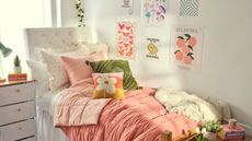 A pink and green dorm room with a bed and wall art