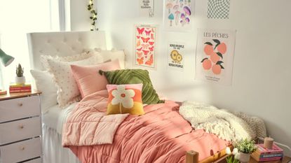 A pink and green dorm room with a bed and wall art