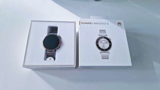 En Huawei Watch GT4 ligger i sin förpackning på ett vitt bord.