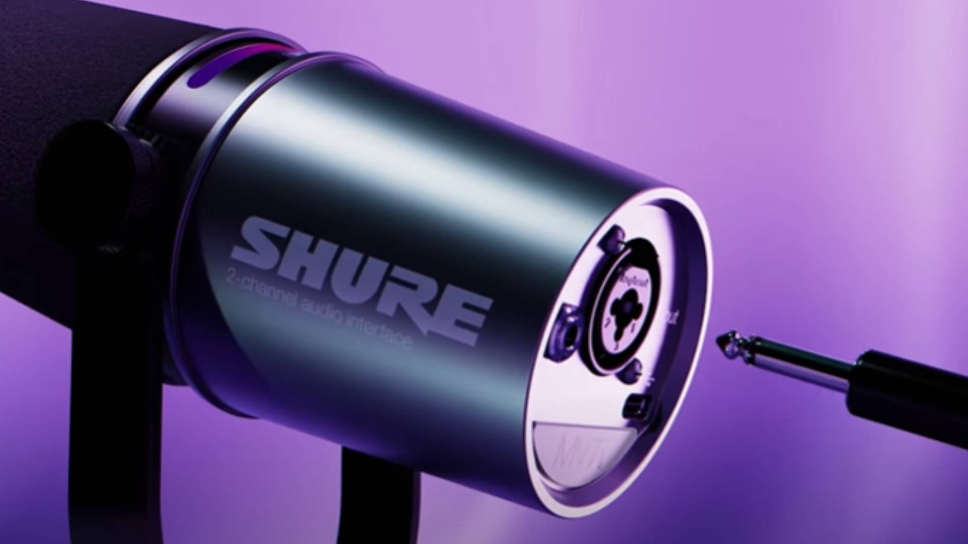 Captura de pantalla del vídeo de YouTube del Shure MV7i, que muestra el puerto XLR en la parte posterior del micrófono sobre un fondo morado.