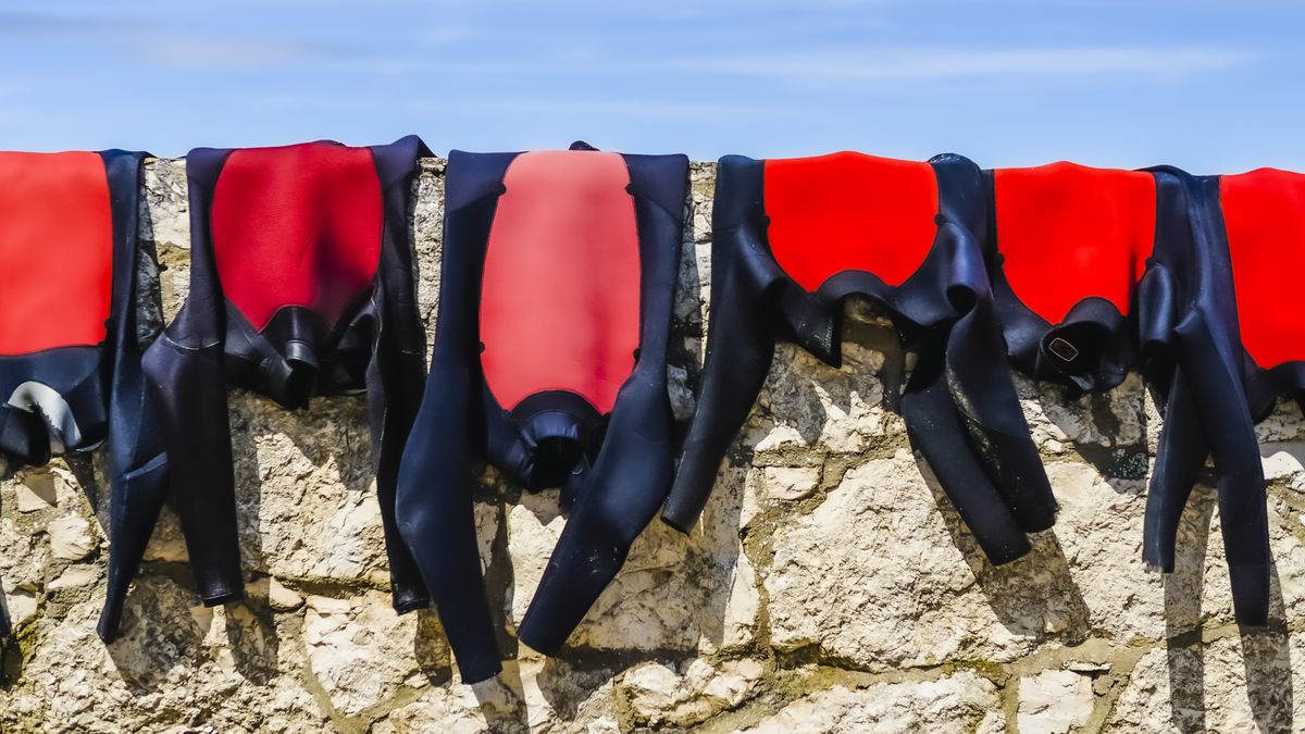 Wetsuits hanging out to dry on a stone wall