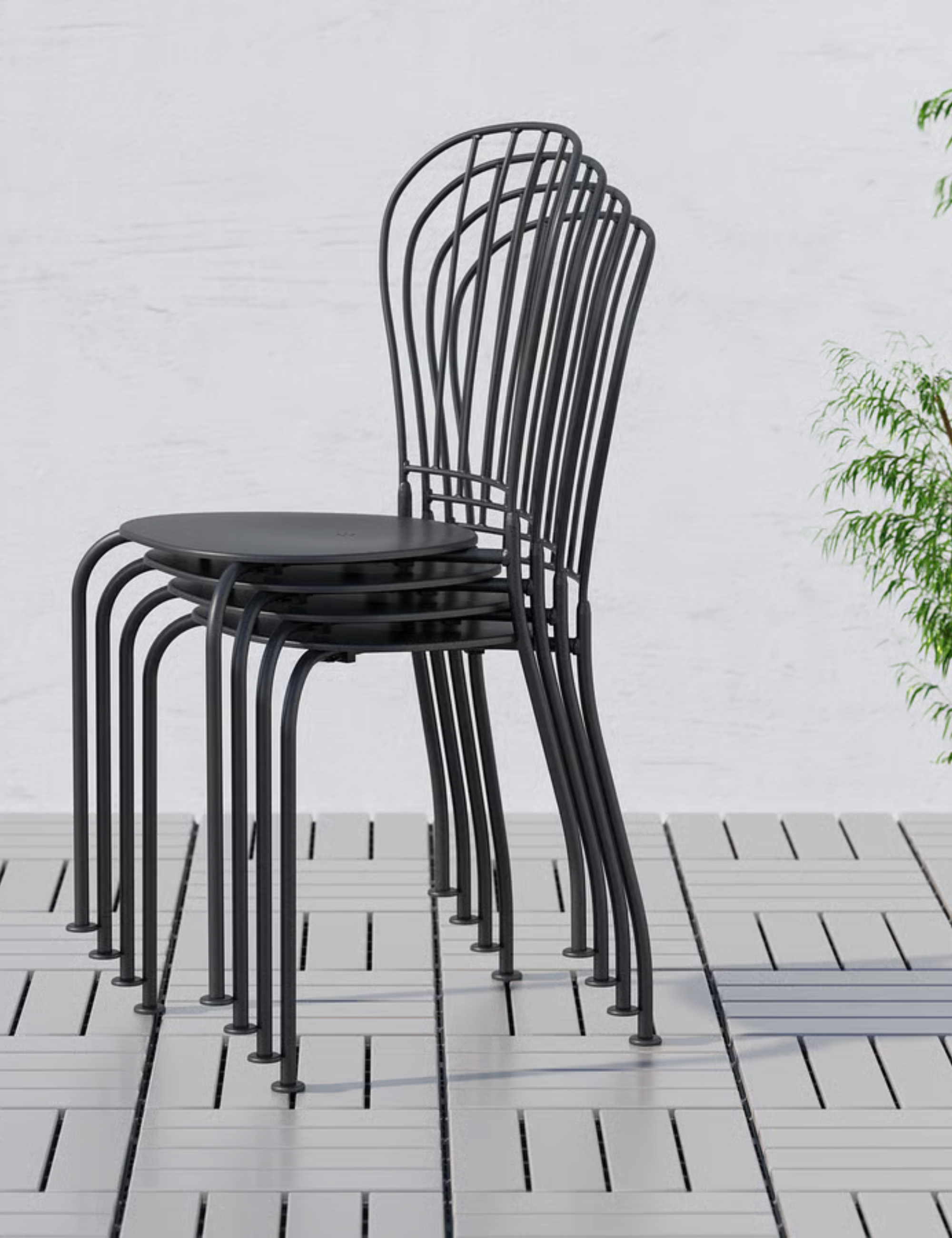 Stack of IKEA Lacko wrought iron outdoor chairs pictured in a grey brick-floored patio