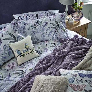 bedroom with purples and dusky pink botanical prints blanket and pillows