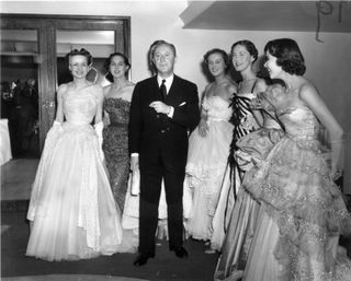 Fashion couturier Christian Dior (1905 - 1957), designer of the 'New Look' and the 'A-line', with six of his models after a fashion parade at the Savoy Hotel, London.