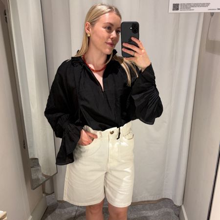 Woman wears black blouse, white shorts 