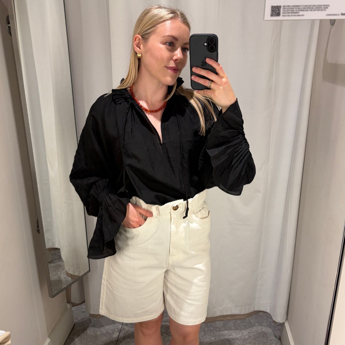 Woman wears black blouse, white shorts 