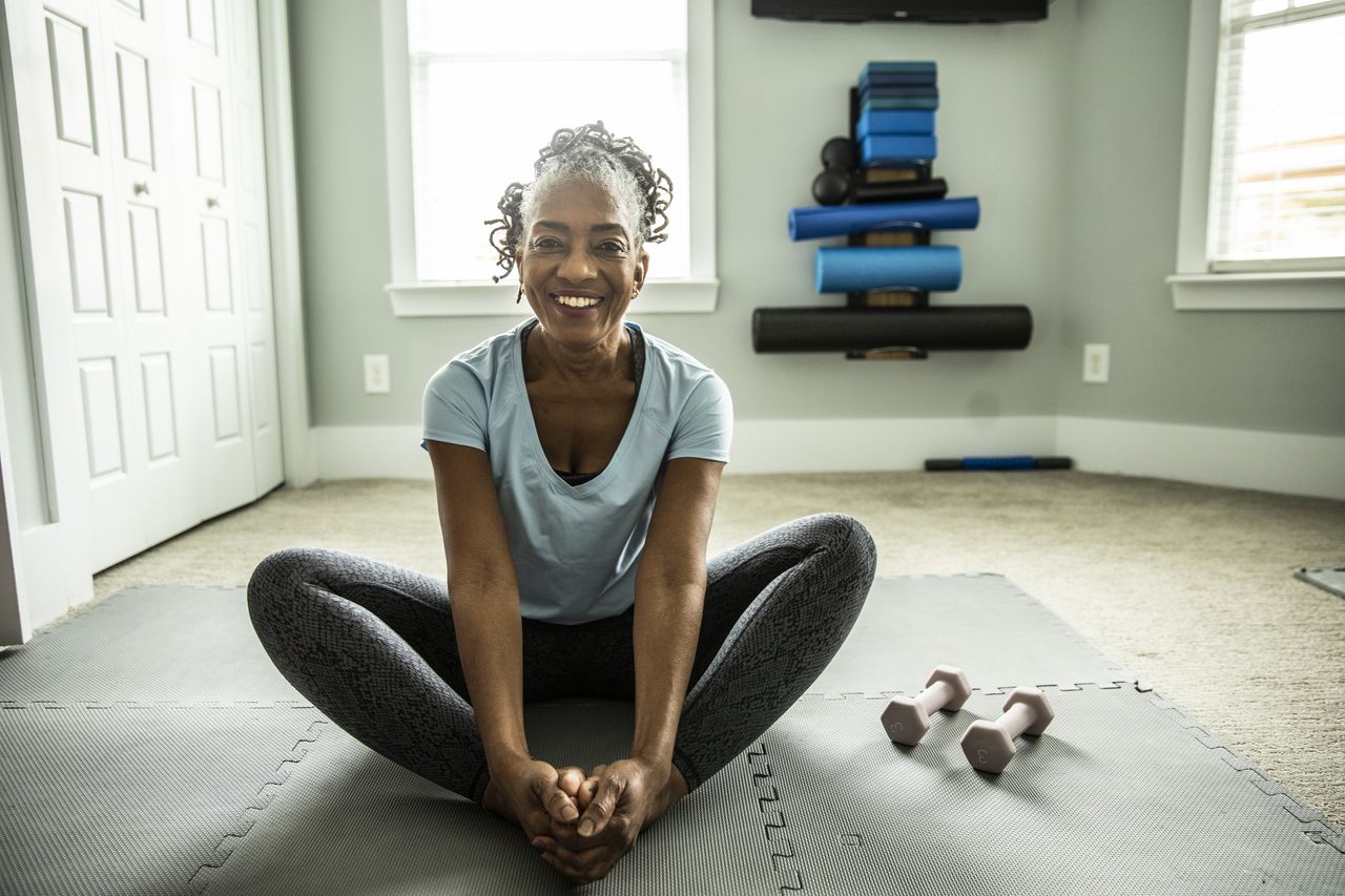 Woman doing a butterfly stretch on the floor in her living room