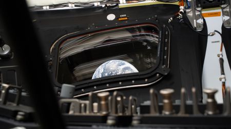 Earth rises through the window from inside a spacecraft