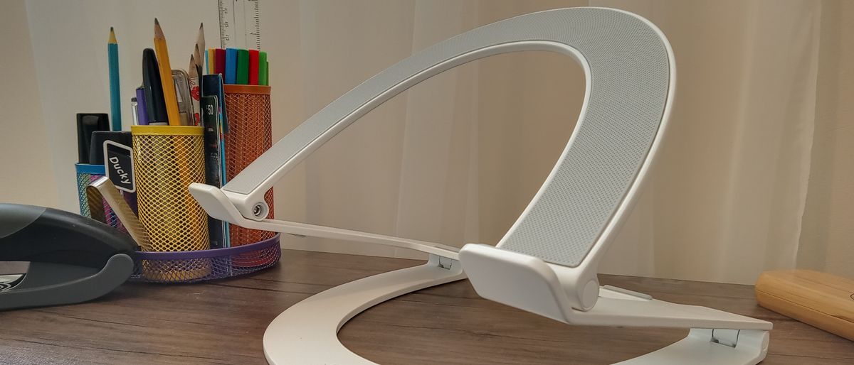 A white z-type Curve Flex laptop stand on a brown desk