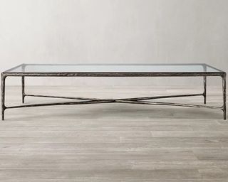 A handforged metal-framed glass coffee table with tempered glass