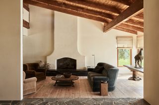 a modern rustic living room with plaster walls and wood floorboards and a dark gray couch