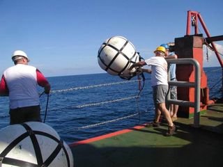To study the rock layers below the seabed, researcher Jamie Austin of University of Texas at Austin and vessel crew deploy a sound source (airguns) and a listening cable