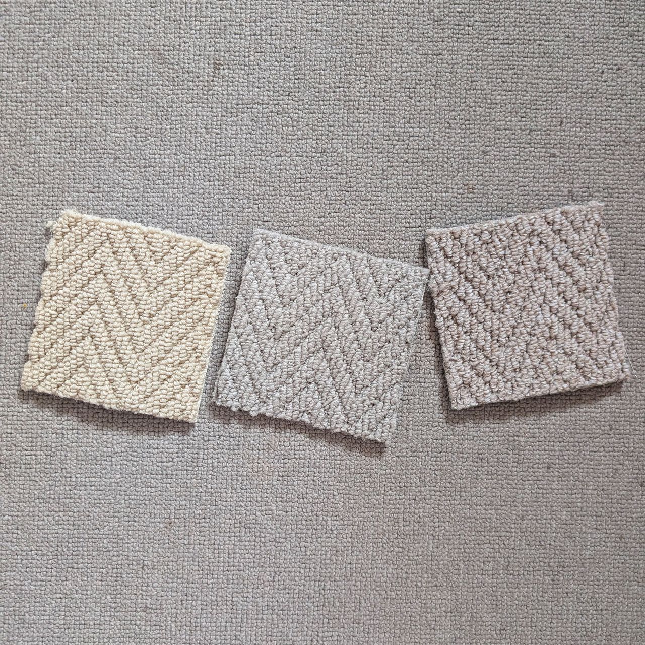 Three square neutral carpet samples sitting on grey carpet