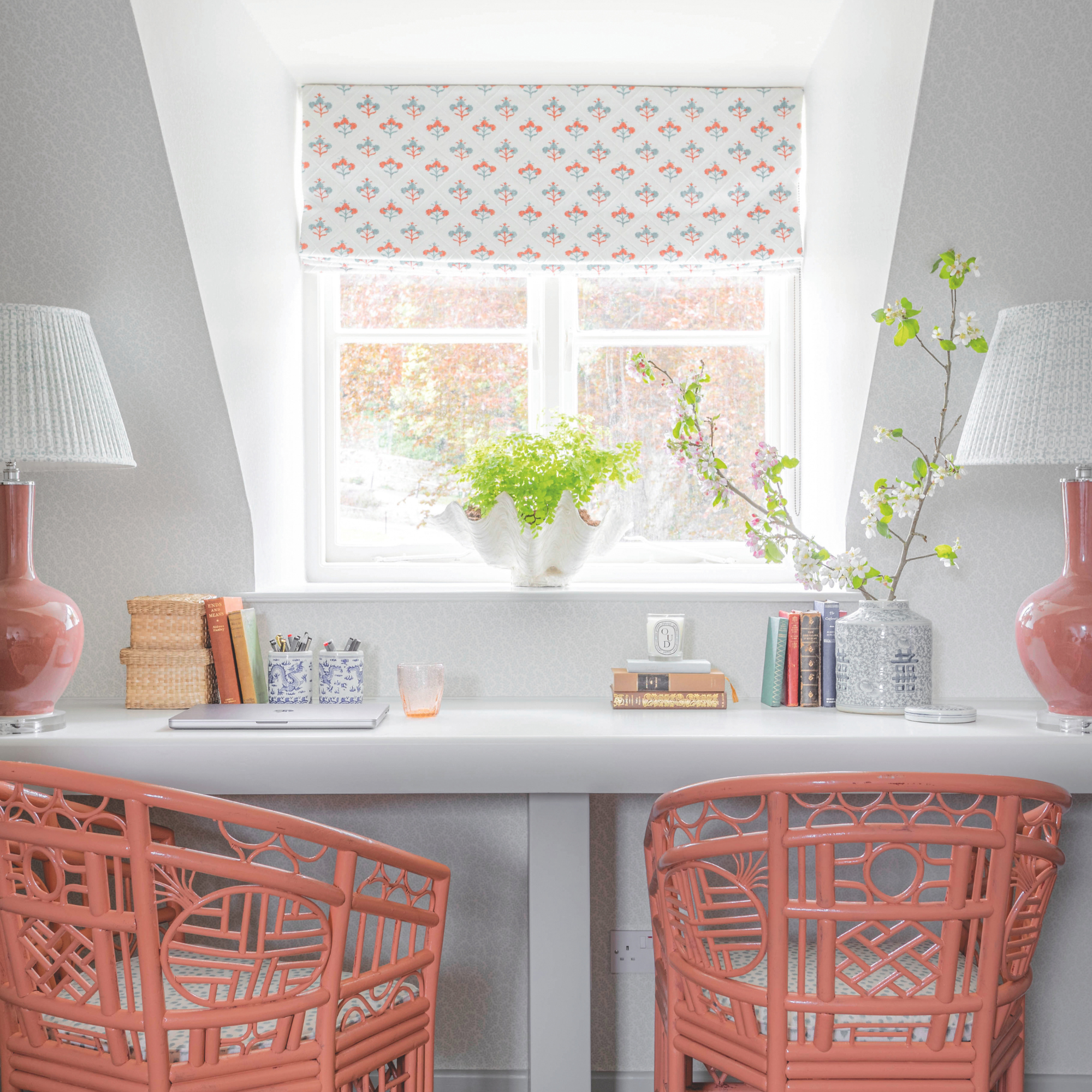 Coral chairs at a desk in front of window with a floral blind.