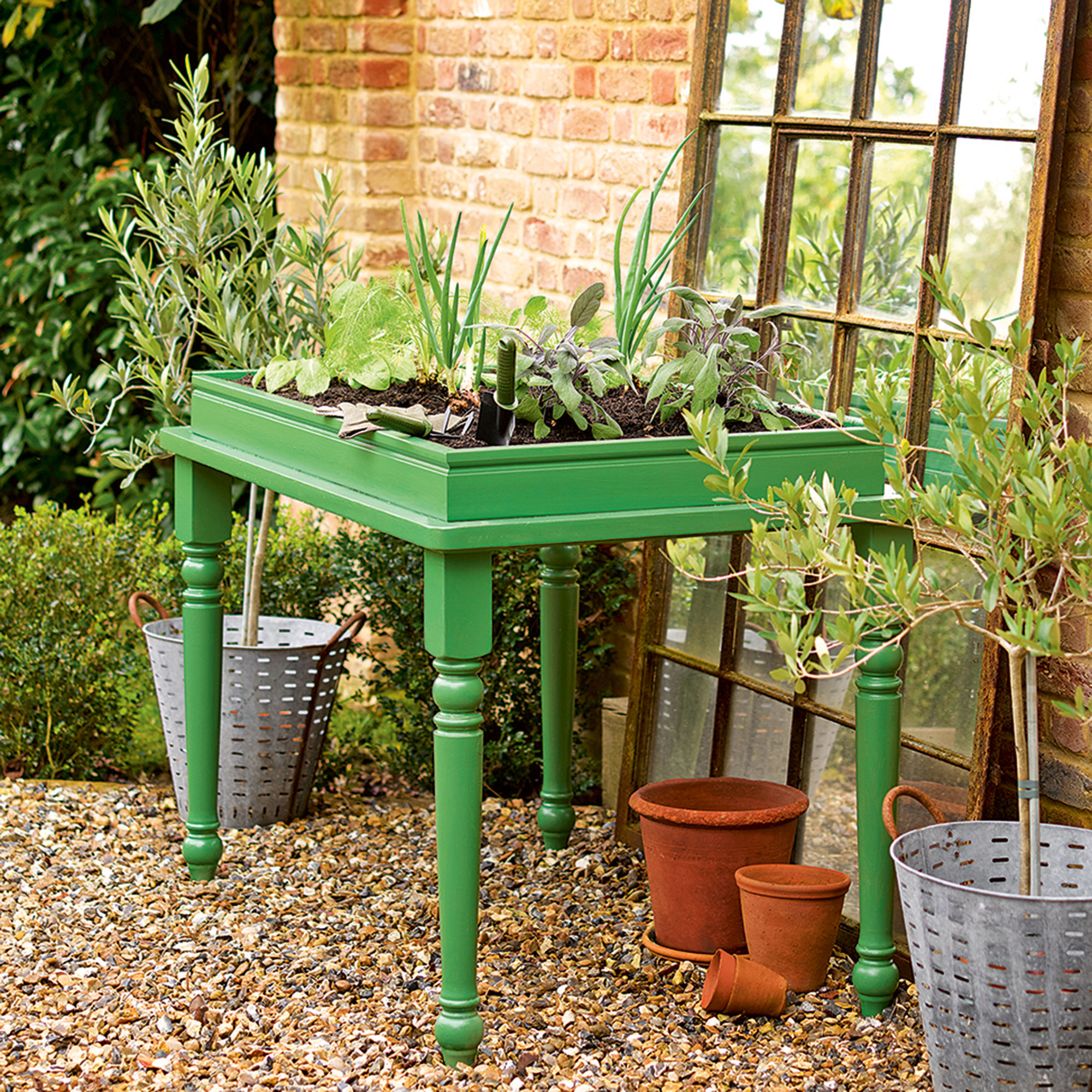 Upcycled green potting table on gravel area in garden