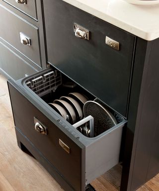 An example of small kitchen storage ideas showing a dark drawer with clever storage for crockery