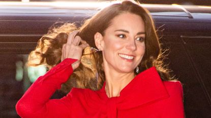 Kate Middleton flicking her hair back wearing a red dress