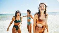 Three women in swimwear laughing in the ocean