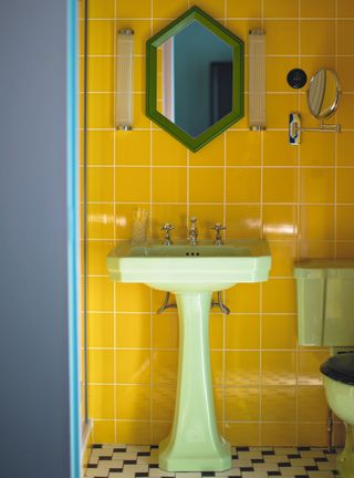 Yellow powder room with glossy yellow tiles and green sanitaryware