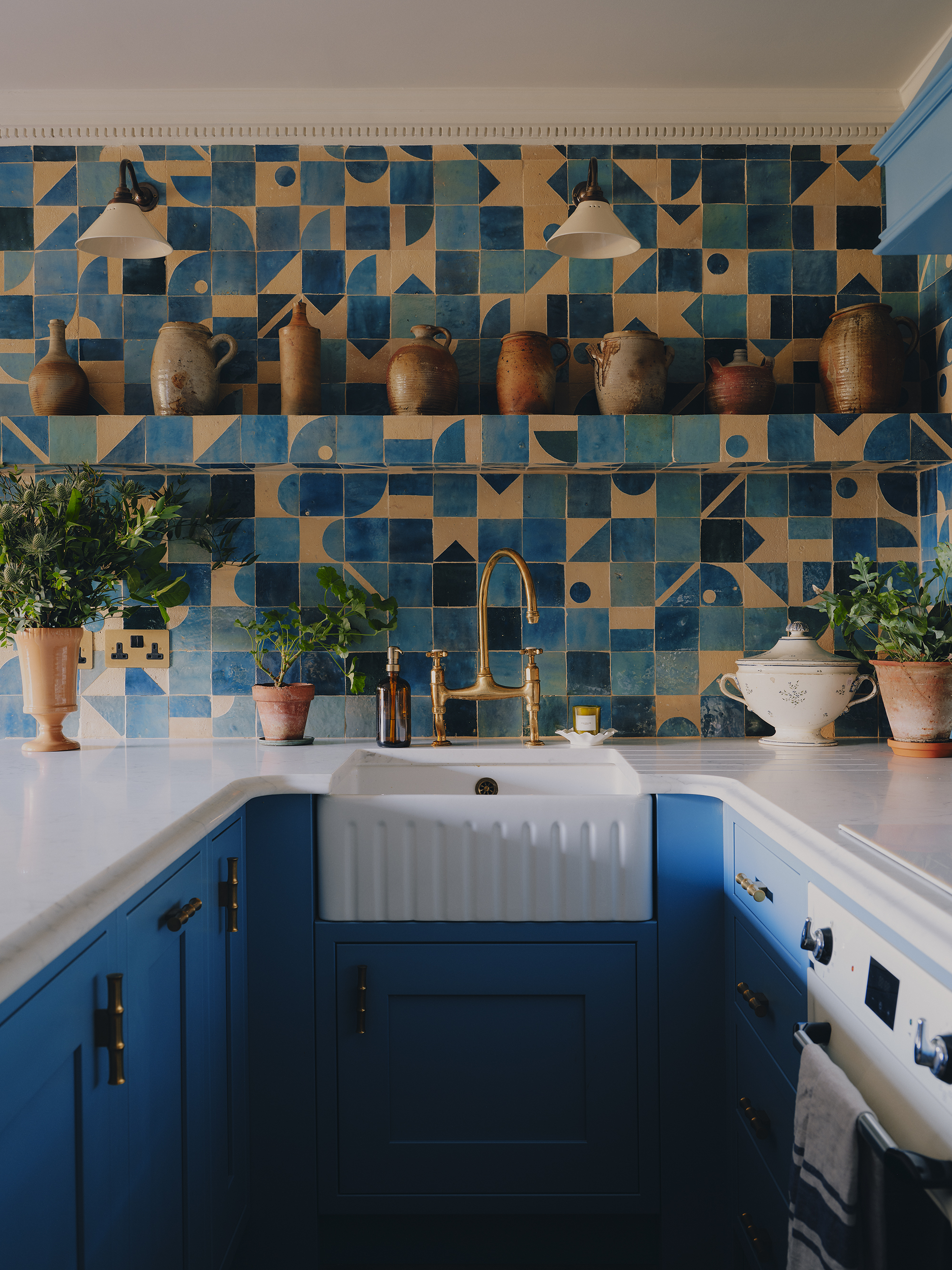 tiny blue kitchen with white counters and a patterned blue tile backsplash