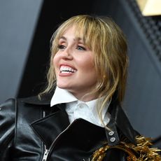 a white woman with blonde hair posing in front of a black background