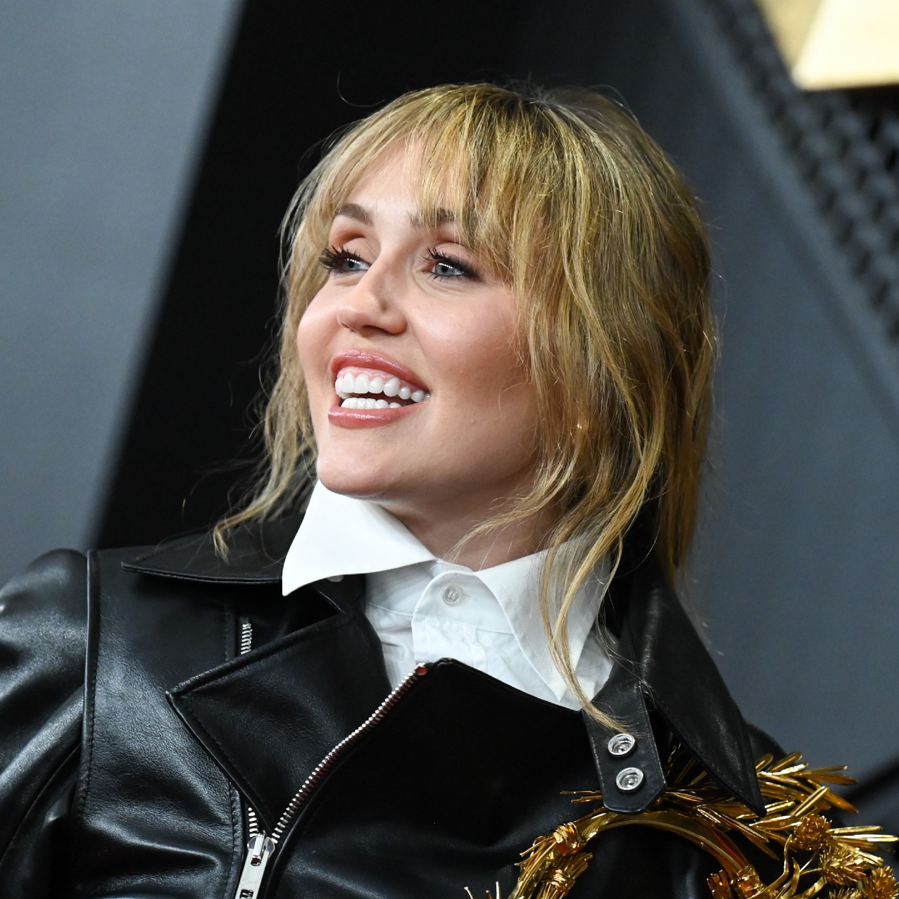 a white woman with blonde hair posing in front of a black background
