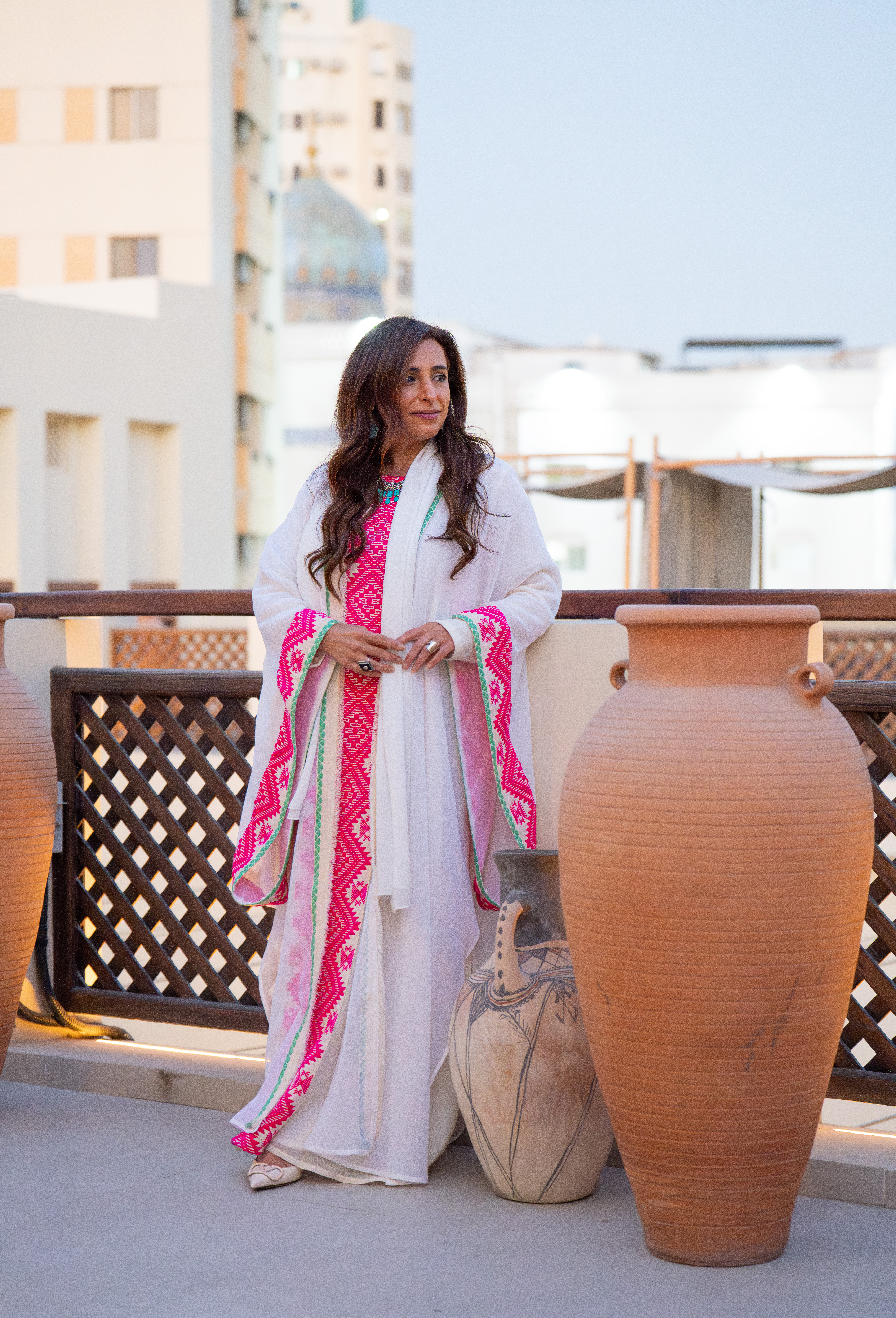 Sheikha Bodour posing in a white caftan by a railing