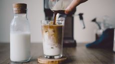 how to make iced coffee from hot coffee: an iced coffee in front of a coffee maker with milk at the side