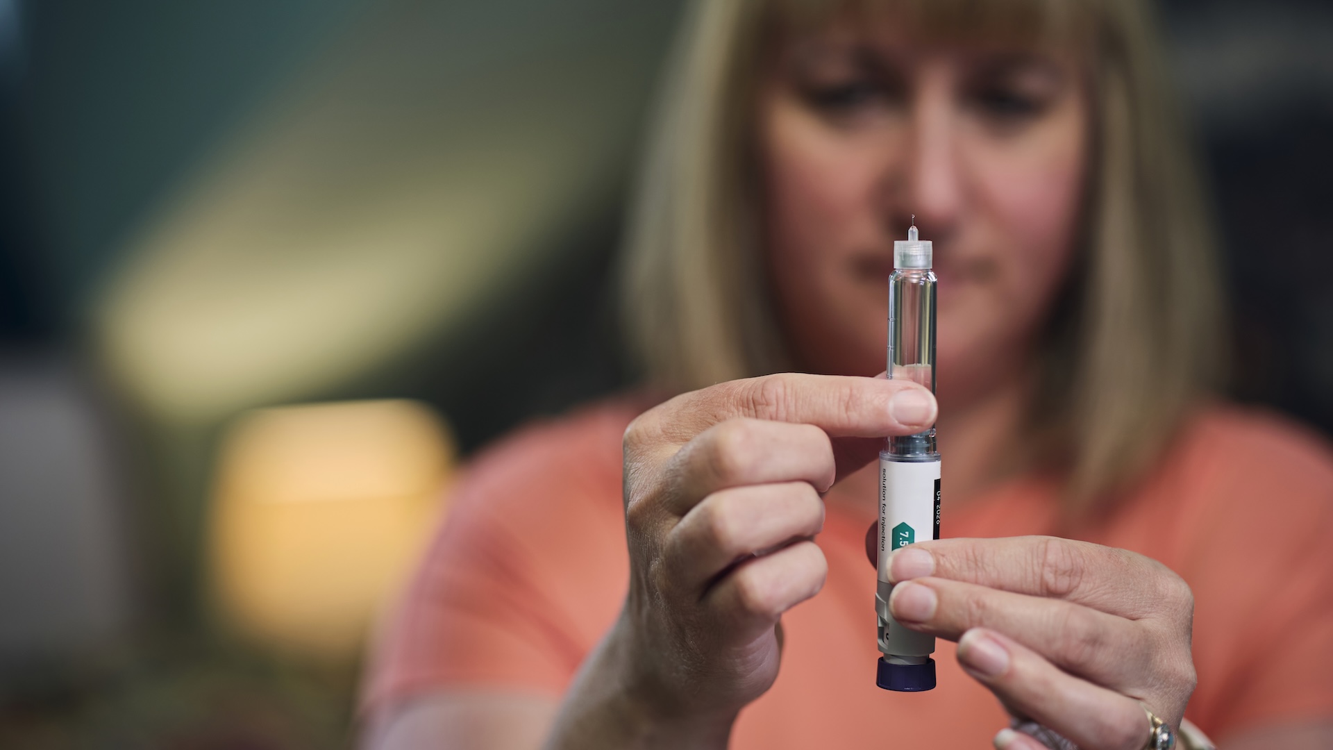 a woman holds up a weight loss drug injector pen