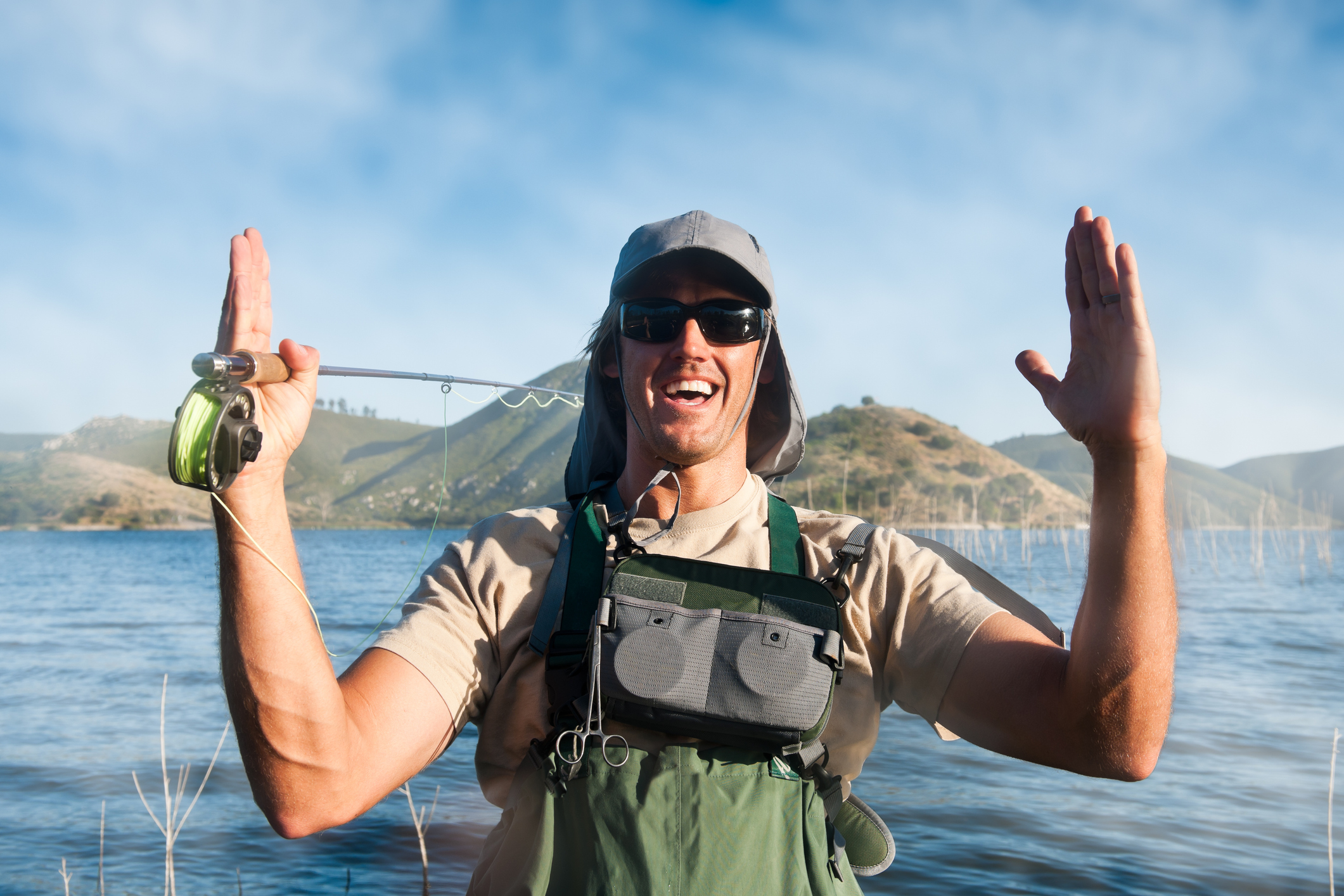 A man dressed in fishing gear using his hands to show the size of the fish that got away. Or a "whopper."