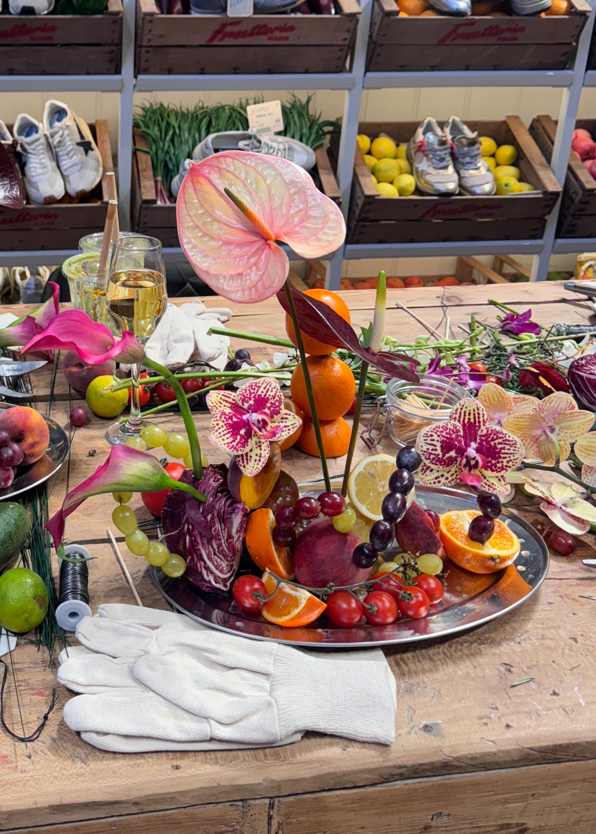 A steel platter with a fruit and floral ikebana arrangement