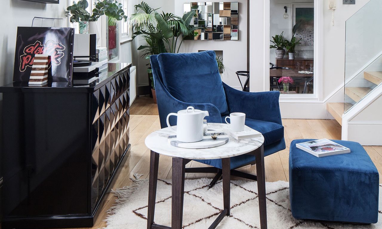 living area with white wall and wooden floor and blue arm chair