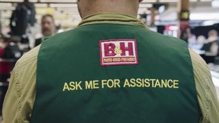 Close-up of the back of a B&H staff member, with the words "Ask me for assistance" across the back of their uniform