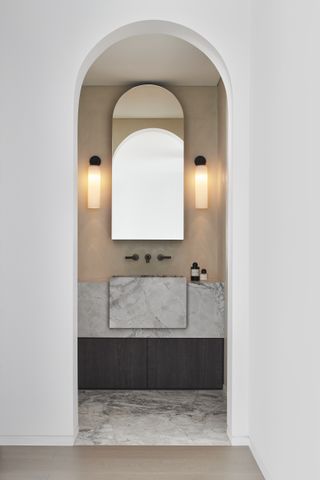 A bathroom with marble sink and limewash walls