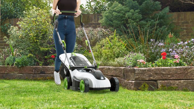 Gtech cordless Lawnmower CLM50 being used by an adult woman to cut her lawn's grass