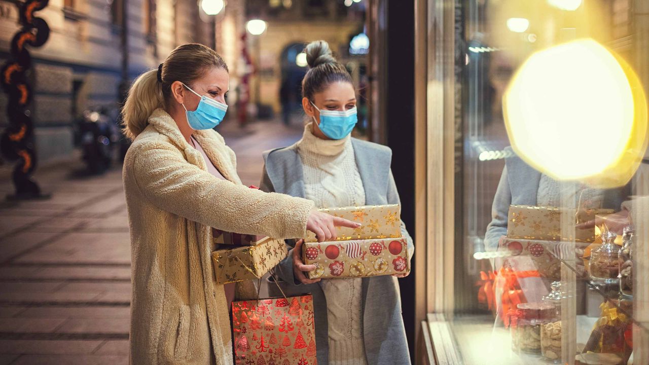 Two women shopping for the holidays wearing face masks.