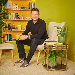 george clarke sitting in armchair in yellow wall room