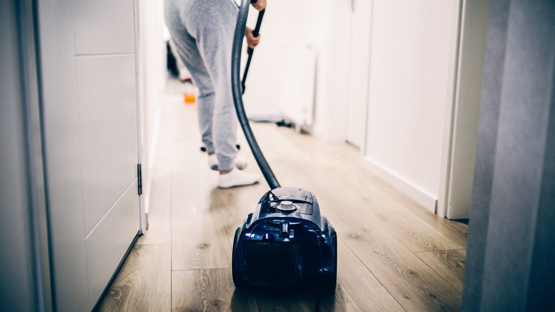 woman cleaning laminate floors with a vacuum cleaner