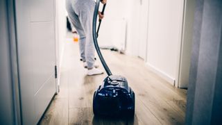 woman cleaning laminate floors with a vacuum cleaner