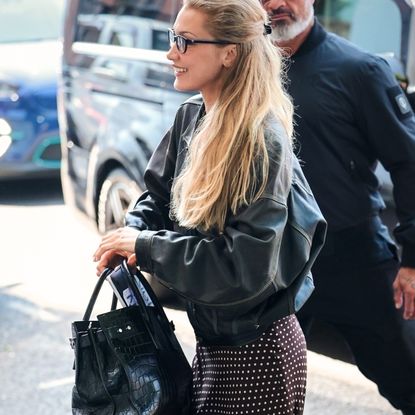 Bella Hadid wearing a polka dot skirt with a saint laurent bag and nike sneakers