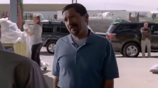 Steven Michal Quezada wearing a blue gold shirt and asking a question to another character in Breaking Bad