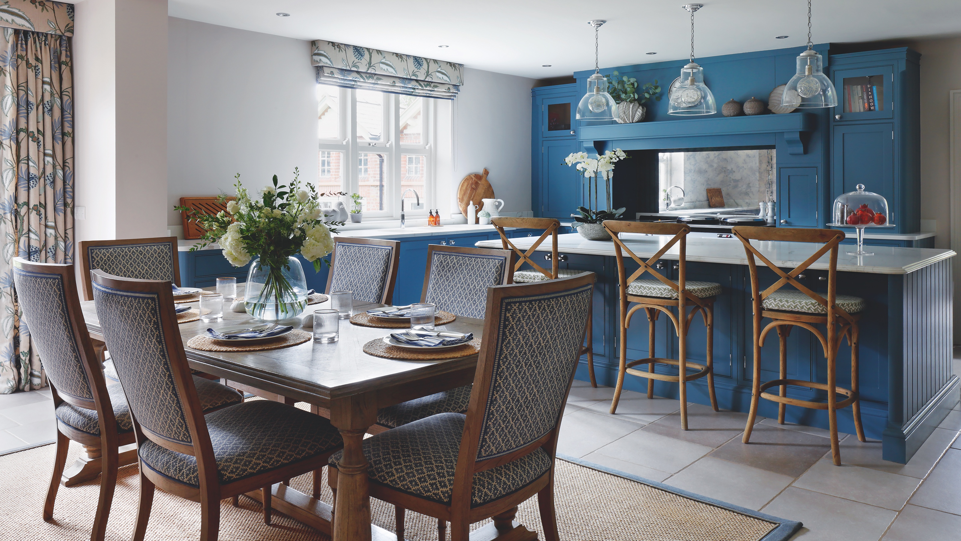 kitchen-diner with blue kitchen units and island, with dining table and upholstered dining chairs