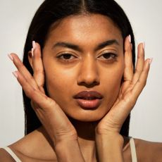 Woman with glowing skin touching her temples 