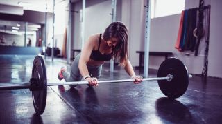Woman performs barbell rollout exercise
