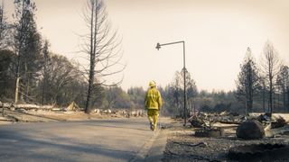 a firefighter walks through a burnt town