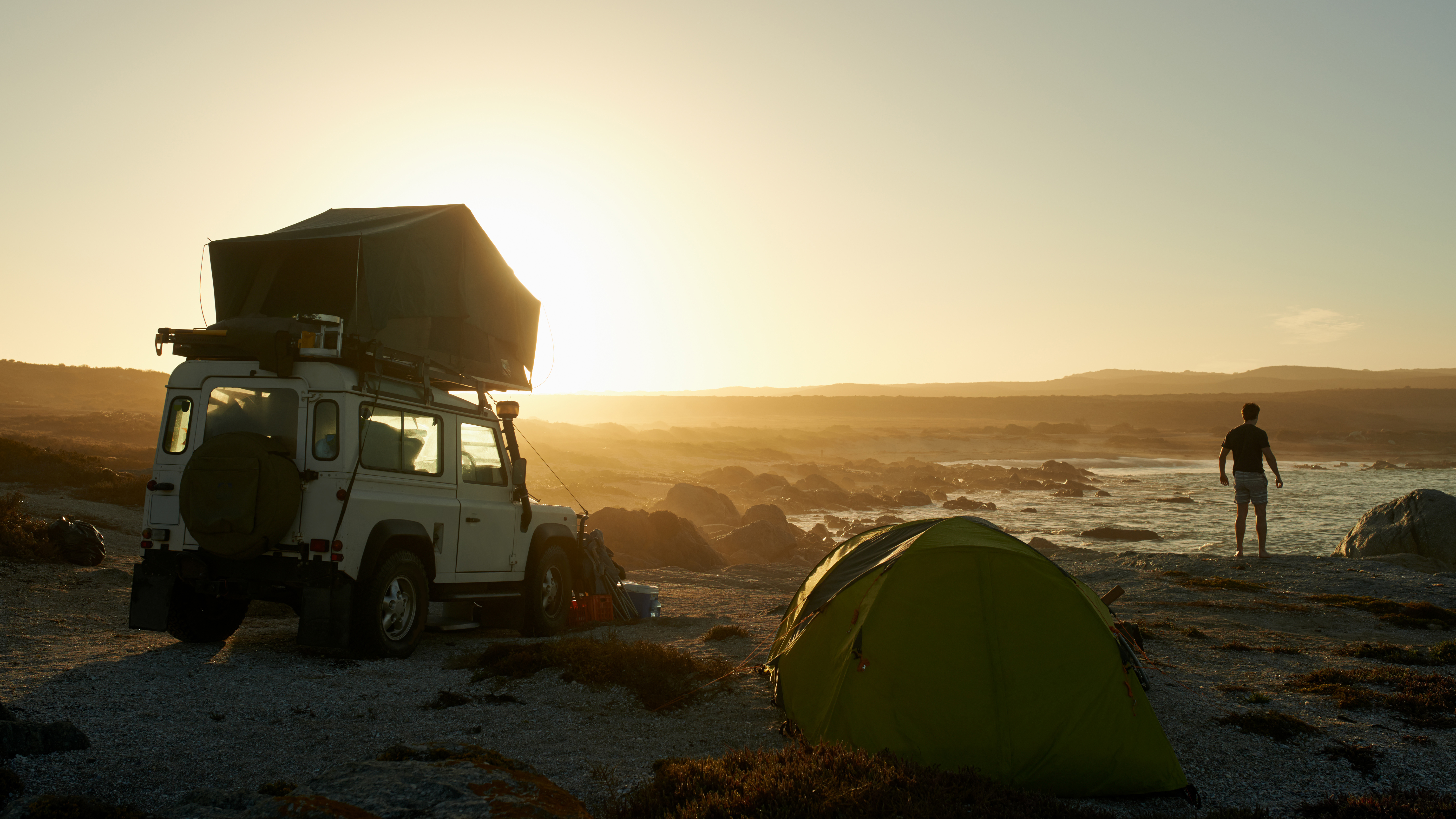 Campers on a beach with a rooftop tent and a standard dome tent