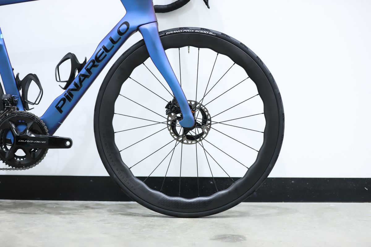 A blue pinarello dogma f stands against a white wall