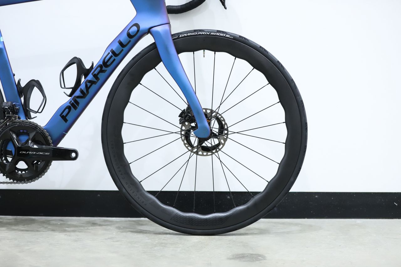 A blue pinarello dogma f stands against a white wall